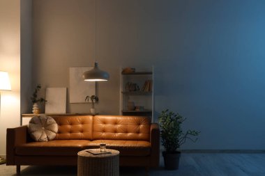 Oturma odasının içinde kahverengi kanepe, raf ünitesi ve akşam lambaları var.