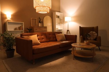 Oturma odasının içinde kahverengi kanepe, koltuk ve gece lambaları var.