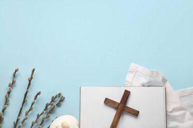 Söğüt dallı ahşap haç, Paskalya pastası ve mavi zemin üzerine boş kitap.