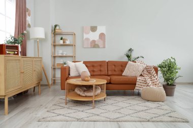 İçinde kahverengi kanepe, masa ve raf ünitesi olan oturma odası.