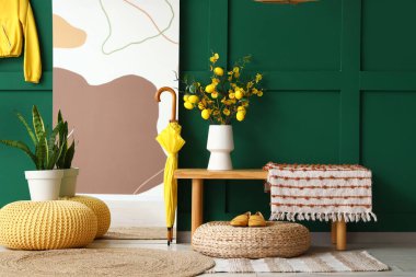 Ayna, vazoda limon dalları ve koridorun iç tarafında bitki örtüsü olan bank.