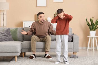 Baba ve oğlu evde ağız dalaşı yaparken kulaklarını kapatıyorlar.