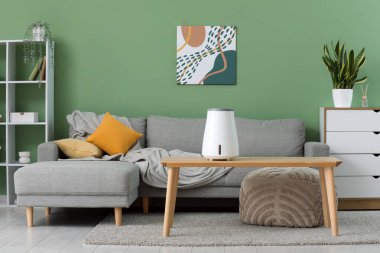 Masasında hava nemlendirici ve kanepe olan bir oturma odası.