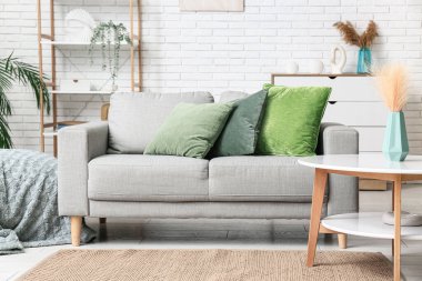 Oturma odasındaki gri koltukta yeşil yastıklar