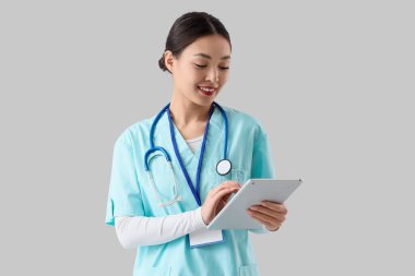 Asyalı kadın doktor, arka planda tablet bilgisayarla çalışıyor. Uluslararası Hemşireler Günü