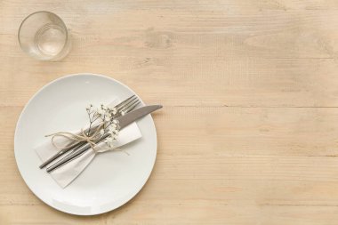 Ahşap zemin üzerinde cam, kağıt peçete ve çatal bıçak tabağı.