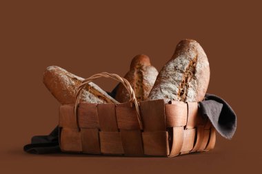 Kahverengi arka planda taze çavdar ekmeği olan hasır sepet.