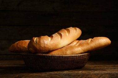 Ahşap zemin üzerinde taze baget olan hasır bir kase.