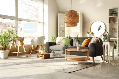 Gri kanepesi, sehpası ve aynası olan şık bir oturma odası.