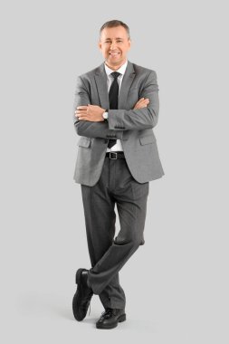 Gri arka planda çapraz kollu olgun iş adamının portresi