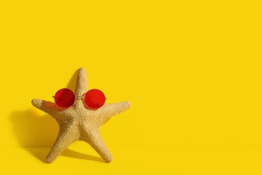 Sarı arka planda şık güneş gözlüklü denizyıldızı