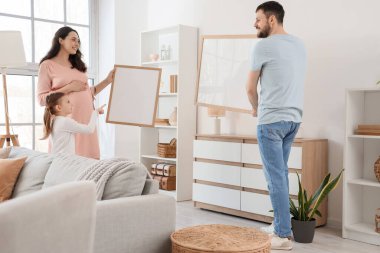 Evde boş kareler asılı mutlu bir aile.