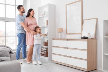 Evinin duvarında boş bir çerçeve asılı mutlu bir aile