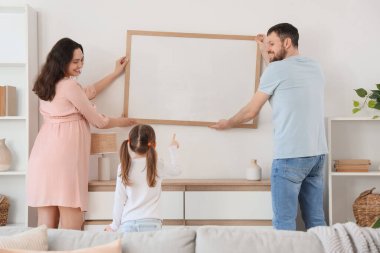 Mutlu bir aile evdeki ışık duvarına boş bir çerçeve asıyor.