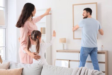 Mutlu bir aile evdeki ışık duvarına boş bir çerçeve asıyor.