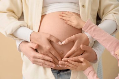 Bej arka planda babasının karnına dokunduğu küçük kız, yakın plan.