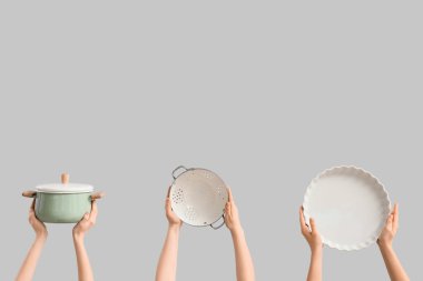 Gri arka planda mutfak aletleri olan kadın elleri