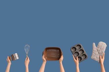 Mavi arka planda mutfak aletleri olan kadın eller.