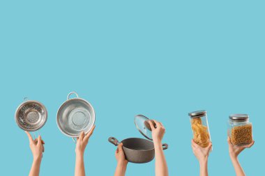 Kolonyalı kadın elleri, tencere ve mavi arka planda makarna kavanozları.