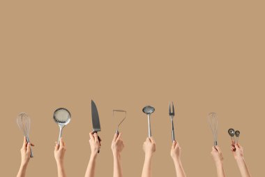 Bej arka planda gümüş mutfak aletleri olan kadın elleri.