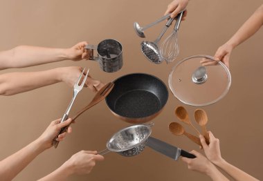 Bej arka planda mutfak aletleri olan kadın elleri