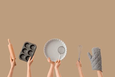 Bej arka planda pişirme aletleri olan kadın elleri