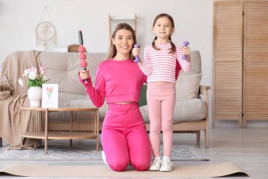 Sportif genç anne ve evde spor aletleri olan sevimli küçük kızı. Anneler Günü kutlaması