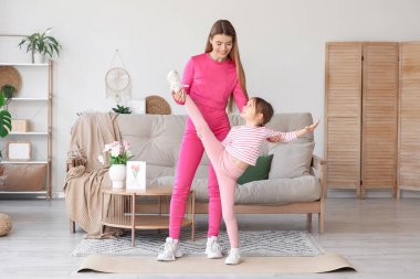 Sportif genç anne ve tatlı küçük kızı evde birlikte egzersiz yapıyorlar. Anneler Günü kutlaması