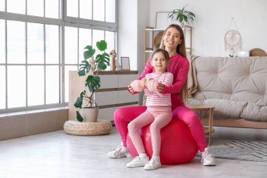 Sportif genç anne ve tatlı küçük kızı evde fitbol oynuyorlar. Anneler Günü kutlaması