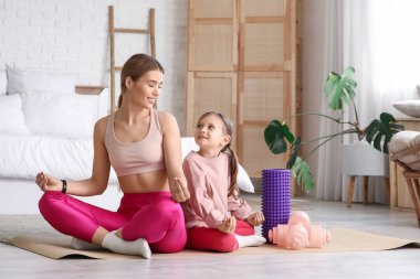 Sportif genç anne ve evde meditasyon yapan küçük tatlı kızı. Anneler Günü kutlaması