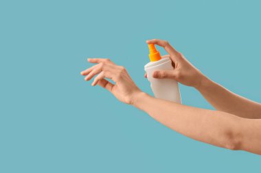 Mavi arka planda güneş kremi süren kadın