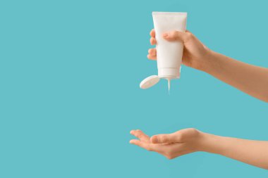 Mavi arka planda güneş kremi süren kadın