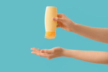 Mavi arka planda güneş kremi süren kadın