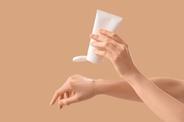 Bej arka planda güneş kremi süren kadın