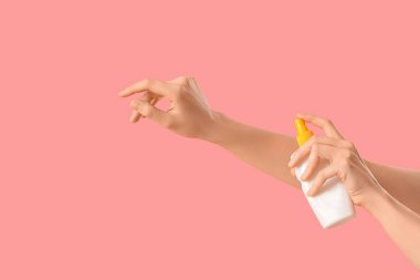 Kadın pembe arka plana güneş kremi sürüyor.