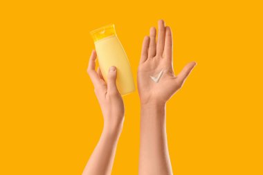 Sarı arka planda, elinde güneş kremi lekesi olan bir kadın.