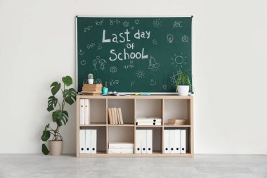 Okulun Son Günü yazılı karatahta, sınıfta çizimler ve raf ünitesi