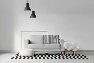 Gri kanepe, puf ve masa ile aydınlık oturma odasının içinde.