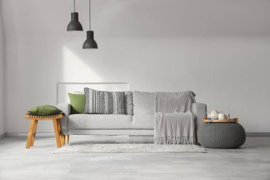 Gri kanepe, puf ve masa ile aydınlık oturma odasının içinde.