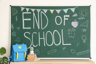 Okul kitaplarının ve metnin yer aldığı sırt çantası sınıftaki tahtanın üzerinde.