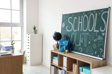 Sırt çantalı raflar, kitaplar, dünya ve metin okulları karatahtada.