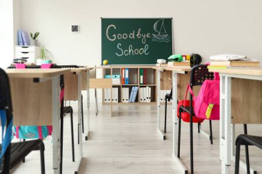 GOODBYE OKULU yazılı karatahta ve sınıf içi aydınlık duvara çizilmiş tekne