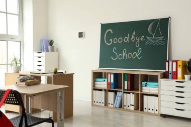 GOODBYE OKULU yazılı karatahta ve sınıf içi aydınlık duvara çizilmiş tekne