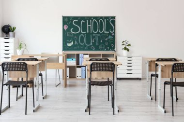 Yazılı karatahta okul kapalı ve sınıfın iç tarafındaki ışık duvarında çizimler var.