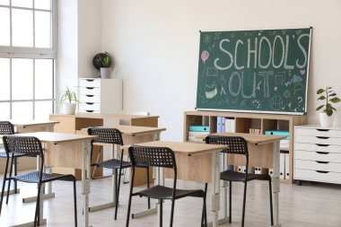 Yazılı karatahta okul kapalı ve sınıfın iç tarafındaki ışık duvarında çizimler var.