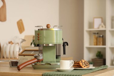 Modern kahve makinesi, fincanlar ve kurabiyeler şık mutfakta, yakın plan.