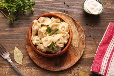 Bir kase lezzetli maydanozlu haşlanmış hamur köftesi ve ahşap arka planda ekşi krema.