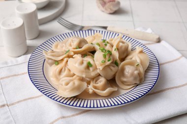 Beyaz fayanslı yeşil soğanlı kaynamış hamur köftesi tabağı, yakın plan.