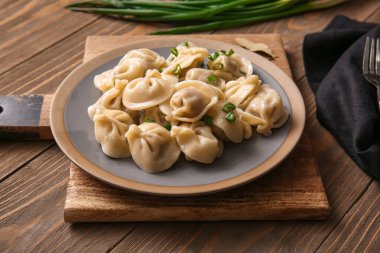 Ahşap arka planda yeşil soğanlı lezzetli haşlanmış hamur köfteleri, yakın plan.