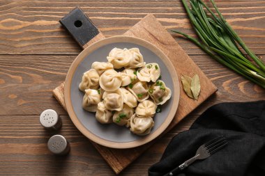 Ahşap arka planda yeşil soğanlı lezzetli kaynamış hamur köfteleri.